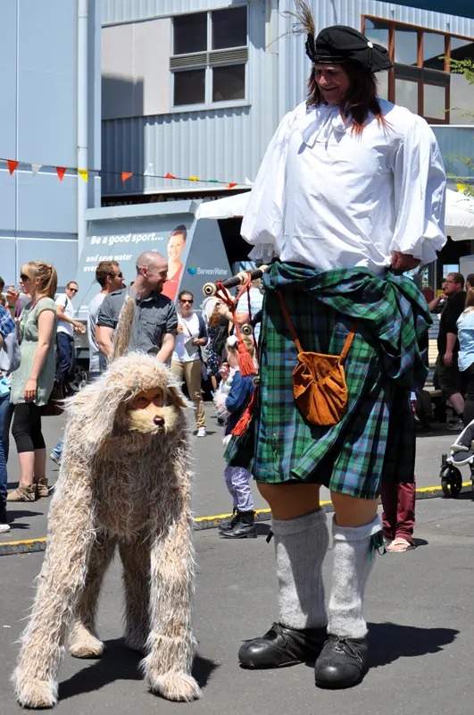 Costumed roving entertainers dress as a large dog and a giast Scotts man 