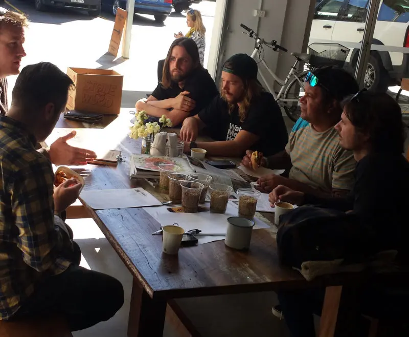 Brewers and artists seated at a table with beer ingredients