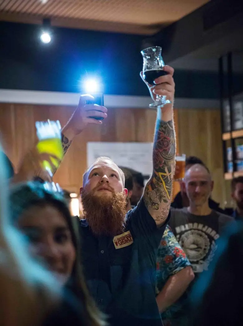 Scotty Beardface holds up a beer