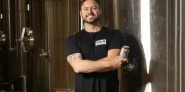 Robert Brajkovich, from Feral Brewing Co., smiling and holding a beer