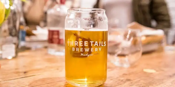 A glass of Three Tails' beer on a table