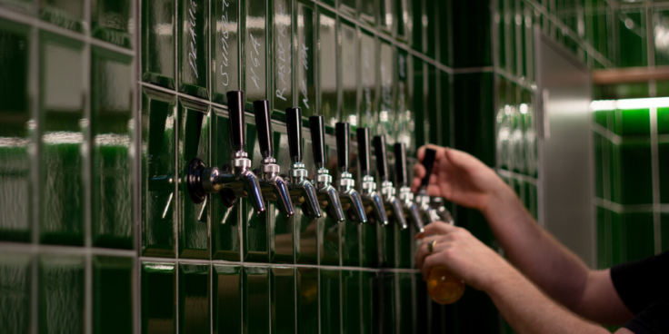 Person pouring beer from beer taps