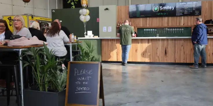 People ordering at the bar at Smiley Brewing's venue