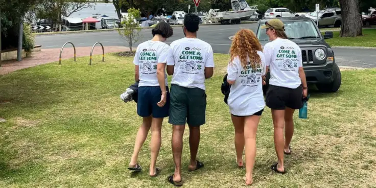 Four people wearing shirts to promote the Co-Conspirators and Alf's Pizza partnership