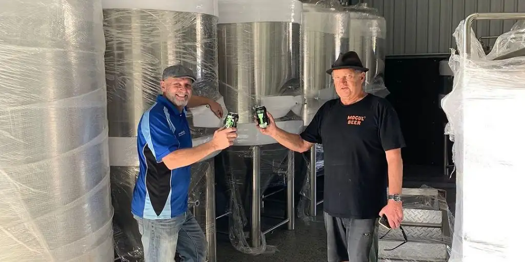 Two men from Mogul Brewing holding up beers