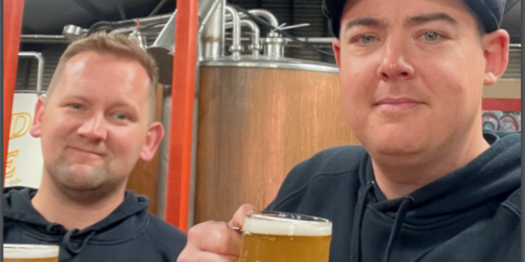 Two Wild Life Brewing staff members holding beers