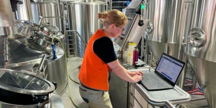 Woman standing at a computer in a brewery