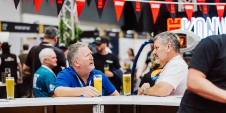 Two men sitting with beers at a bar
