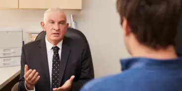 Man in a suit talking to a teenager